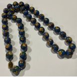 A string of 44 spherical cloisonne beads, each in blue with flowering stems
