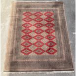 A Middle Eastern rectangular woollen rug or carpet, geometric lozenges and motifs, in tone of red,