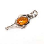An Art Nouveau style silver brooch, the centre set with an amber type cabochon