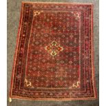 A Middle Eastern woollen rug or carpet, geometric floral motifs, in tones of red, blue and ochre,