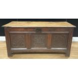 An early 18th century oak blanket chest, hinged top above a three panel front carved with floral and