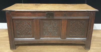 An early 18th century oak blanket chest, hinged top above a three panel front carved with floral and