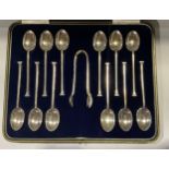 A set of twelve George V silver teaspoons, monogrammed stepped terminals, a pair of sugar bows en