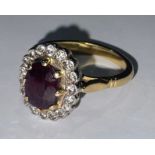 An 18ct gold, diamond and ruby ring, stamped '18ct' for 18ct gold, the central facet cut oval