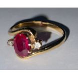 A ruby and diamond three stone 18ct gold ring, the central oval cut ruby flanked by two old