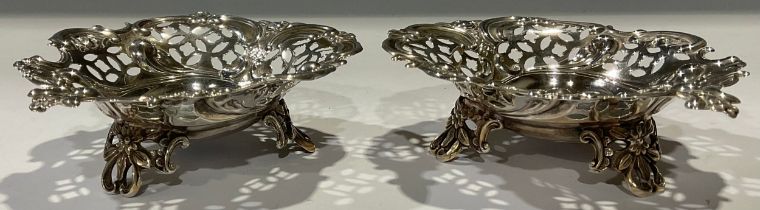 A pair of late Victorian silver heart shaped bon-bon dishes, pierced borders, three scroll feet,