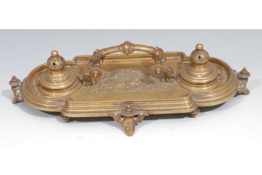 A Victorian brass inkstand, in the Renaissance Revival taste, central arched handle terminating in - Image 1 of 3