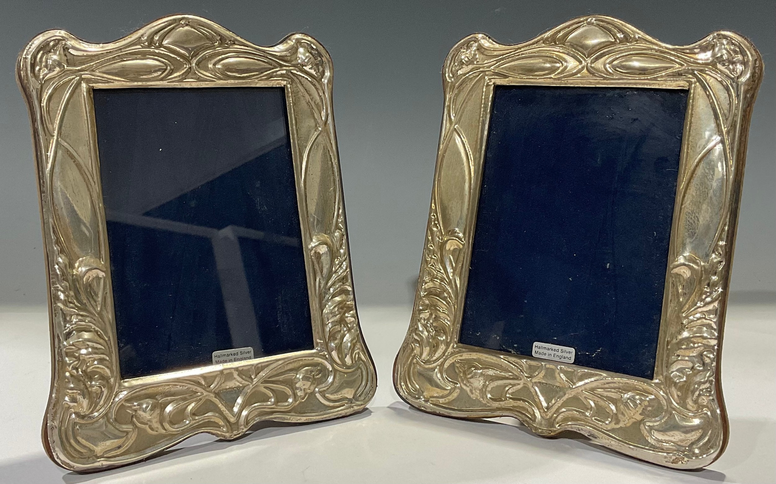 A pair of Elizabeth II silver Art Nouveau style arched easel photograph frames, embossed with