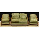 An early 20th century oak three-piece bergère drawing room suite, comprising a sofa and a pair of