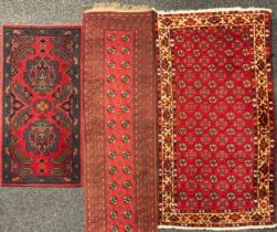 A Middle Eastern woollen rug or carpet, decorated with geometric shapes in tones of red and brown,