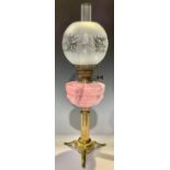 A brass oil lamp, opaque pink glass reservoir, Duplex twin burner, ovoid acid etched frosted glass