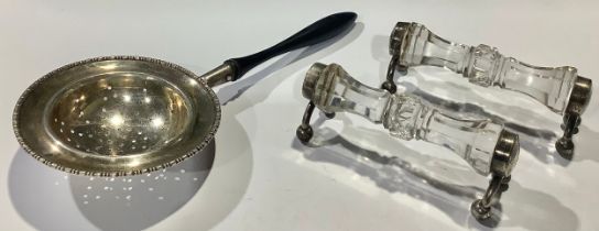 A pair of George V silver mounted knife rests, Chester 1930; a silver tea strainer, Birmingham