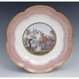 An 18th century Sevres six lobed dish, painted with figures beside a river beneath castle ruins,