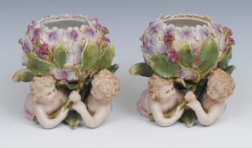 A pair of Continental porcelain vases, each modelled with flowers supported by scantily clad