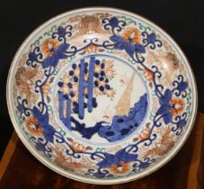 A Japanese circular dish, painted in the Imari palette in the Chinese manner with bats, flowers