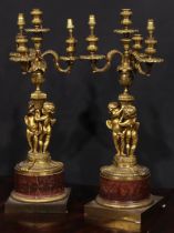 A pair of French gilt bronze figural five light candelabra, the pillars cast with putti, marble