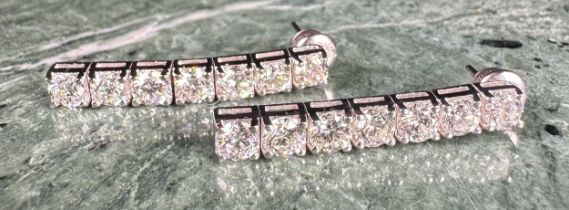 A pair of 18ct white gold and diamond drop earrings, each set with seven round brilliant cut claw