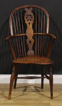 A 19th century beech, ash and elm Windsor elbow chair, hoop back, wheel splat, saddle seat, turned