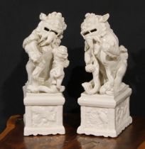 A pair of Chinese blanc de chine models, of temple dogs, each base moulded in relief with horses,