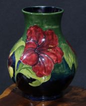 A Moorcroft Hibiscus pattern ovoid vase, typically tubelined on a green ground, 25cm high, script