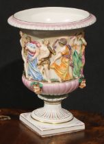 A Naples porcelain campana shaped mantel urn, moulded in relief with classical figures dancing and