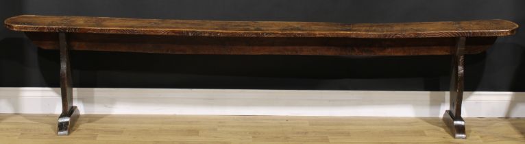 A Provincial vernacular elm table-length bench, shaped end supports, sledge base, 47cm high, 225cm