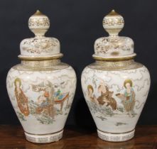 A pair of Japanese Satsuma temple jars and covers, gilt and painted in the typical palette with