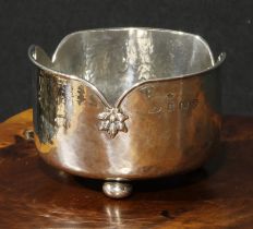 A E Jones - an Arts and Crafts silver bowl, shaped rim with stylised leafy bosses, planished
