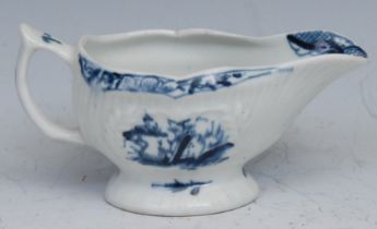 A Lowestoft butter boat, pleat moulded, painted in underglaze blue with landscapes, the interior