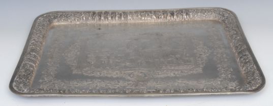 An Iranian silver coloured metal rounded rectangular tray, chased and engraved with persian