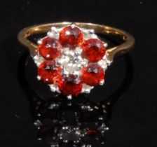 A diamond and garnet floral cluster ring, central brilliant cut diamond approx 0.25ct, surrounded by