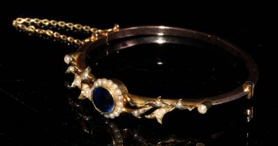 A late 19th/early 20th century 15ct gold hinged bangle bracelet, set with a central synthetic