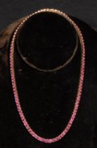 A 14ct gold tennis necklace, with one hundred and six square claw set rubies, 3.5mm each, box snap