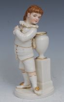 A Royal Worcester figure, of a boy stood next to a vase and pedestal, picked out in flesh tones