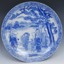A Japanese circular charger, decorated in tones of underglaze blue with elders in a pagoda