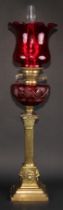 A 19th century brass oil lamp, Corinthian column, cranberry reservoir, twin-burner, fluted cranberry