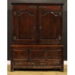 An 18th century oak bacon press or housekeeper’s cupboard, outswept cornice above a pair of arched