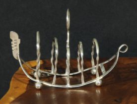 An Edwardian silver novelty five bar toast rack, as a Venetian gondola, ring handle, ball feet, 13.