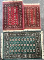 A large woven Bokhara type rug, in shades of green; two others similar, smaller, in shades of red (