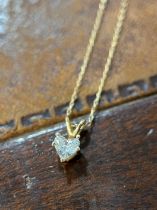 A gold coloured metal and white stone heart shaped pendant, the stone possibly white sapphire, the