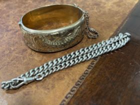 A gold on silver hollow cast hinged bangle, engraved and chased with foliate scrolls, 6.2cm in