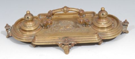 A Victorian brass inkstand, in the Renaissance Revival taste, central arched handle terminating in