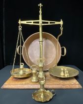 A set of brass balance scales; a set of graduated brass bell weights; a large copper two-handled