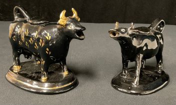 A Jackfield type cow creamer and cover, in black, picked out in gilt, oval base, 13cm high, c.