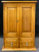 A mahogany collector's cupboard, the pair of fielded doors above two drawers, brass drop handles,
