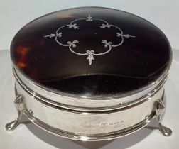 A George V silver circular dressing table box, the hinged cover with silver inlaid tortoiseshell,