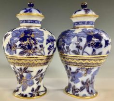 A pair of Wedgwood inverted baluster flow blue urnular vases and covers, printed with foliate stems,