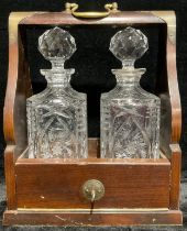 A two bottle tantalus, containing two cut glass decanters, brass carry handle, 37cm high over handle