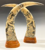 A pair of carved buffalo horns, engraved in low relief with tigers, dragons and fanciful birds,