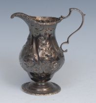 An 18th century silver baluster cream jug, wrythen fluted and chased with flowers and foliage,